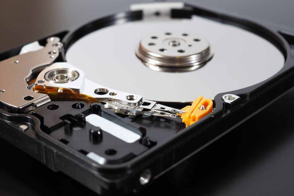 A disassembled open hard disk drive HDD of a computer or laptop lies on a dark matte surface. Close-up. IT&C. Illustration: computer hardware and equipment.
